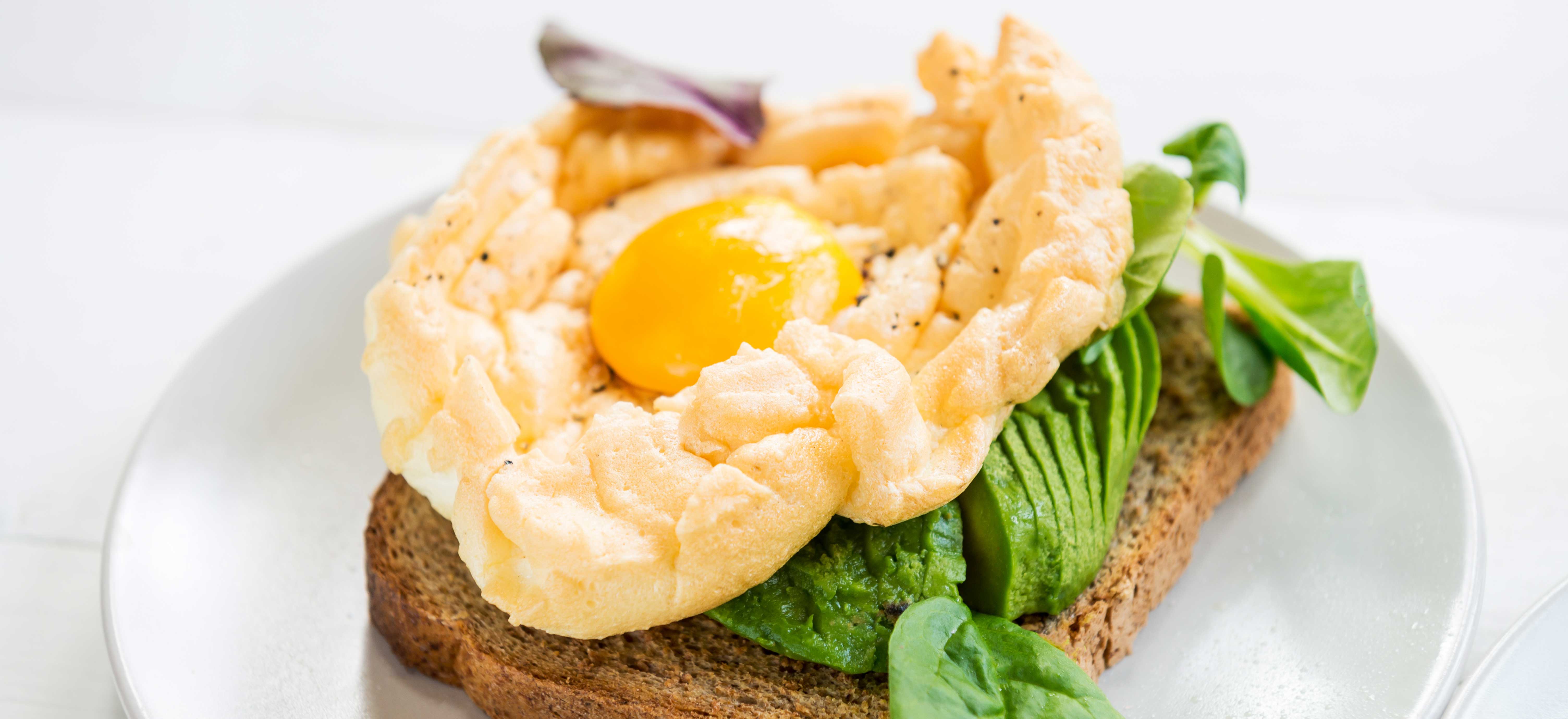 Cloud eggs met avocado en veldsla op geroosterd brood
